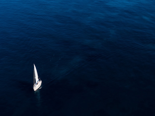 Toma aérea de un pequeño bote blanco navegando en el océano