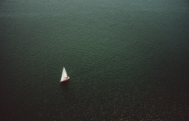 Toma aérea de un pequeño bote navegando en el hermoso océano ancho