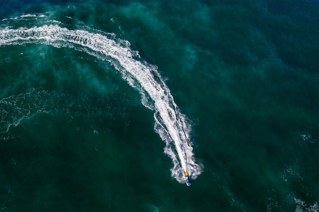 Toma aérea de una persona en moto acuática en agua de mar verde brillante