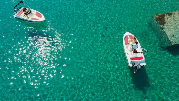 Toma aérea de personas conduciendo lanchas en un mar transparente