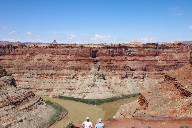 Toma aérea de personas de pie en una colina mirando hacia un acantilado del desierto durante el día