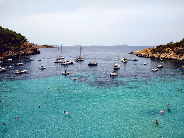 Toma aérea de la playa cerca de Ibiza llena de barcos y gente