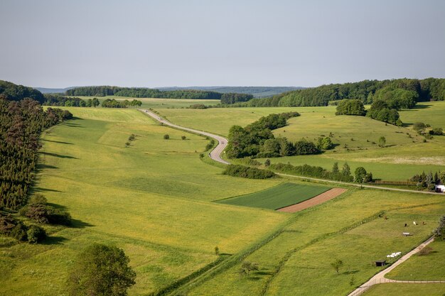 Toma aérea de tierras de cultivo bajo el cielo despejado en la región de Eifel, Alemania