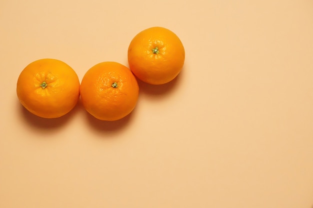 Toma aérea de tres deliciosas frutas naranjas con color naranja de fondo