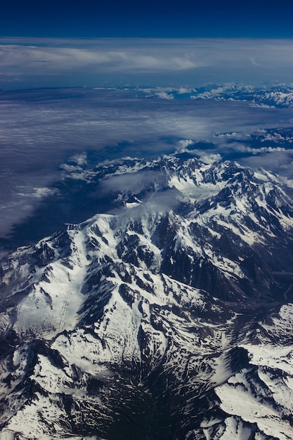 Toma aérea vertical de paisajes nevados montañosos bajo el impresionante cielo azul
