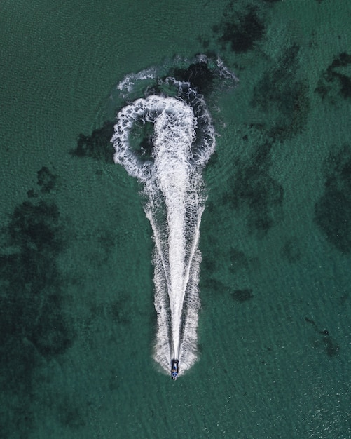 Toma aérea de un yate navegando en el mar dejando huellas de salpicaduras