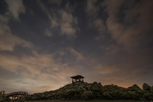 Toma en ángulo bajo de un pequeño refugio en la cima de una colina rocosa y horizonte al atardecer en Corea del Sur