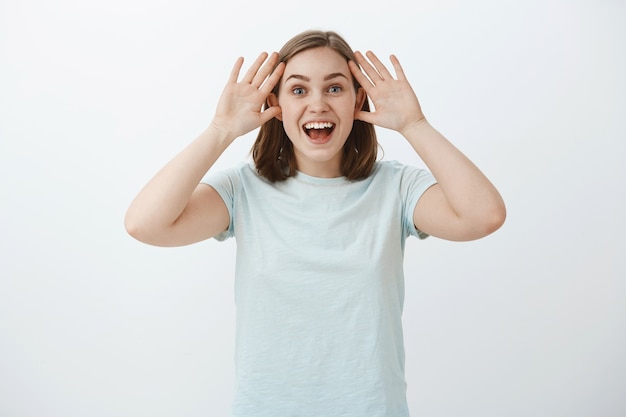 Toma de cintura para arriba de una mujer sorprendida y complacida que no puede creer que ganó el viaje participando en la competencia sosteniendo las palmas cerca de la cara sonriendo ampliamente y emocionada mirando con mirada de ensueño y encantada