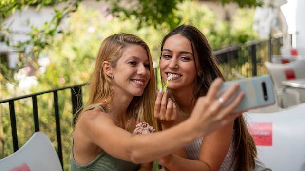 Toma de enfoque selectivo de chicas jóvenes atractivas tomando un selfie en un café