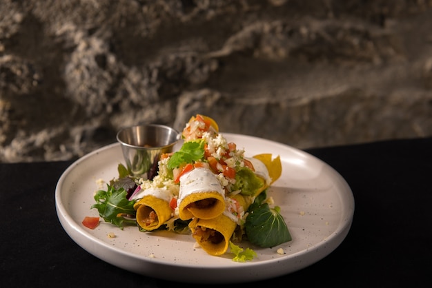 Toma de enfoque selectivo de deliciosas flautas de cerdo al estilo mexicano en una placa blanca.