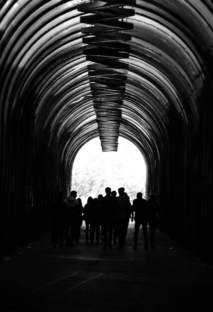 Toma en escala de grises de un grupo de personas caminando por el túnel arqueado en Ereván Armenia