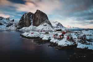 Foto gratuita toma horizontal de una ciudad costera con casas rojas cerca de un mar y una montaña nevada en la parte posterior