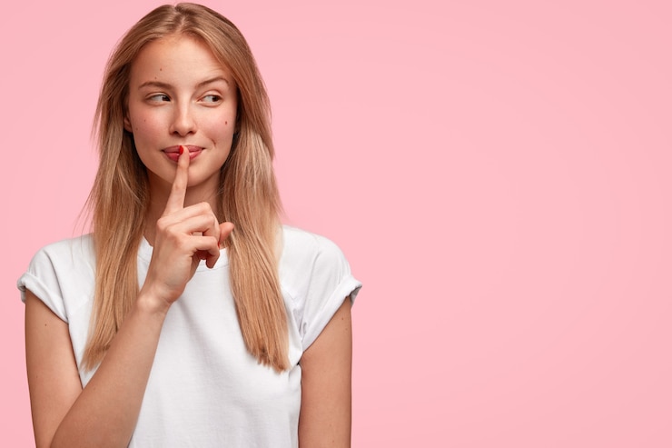 Foto gratuito toma interior de una mujer hermosa que se ve misteriosamente a un lado, tiene un aspecto intrigante, pide estar en silencio,