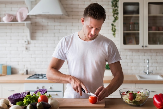 Foto gratuita toma mediana hombre cortando tomate