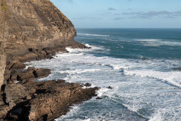 Toma de paisaje de una impresionante costa rocosa con acantilados y olas enojadas