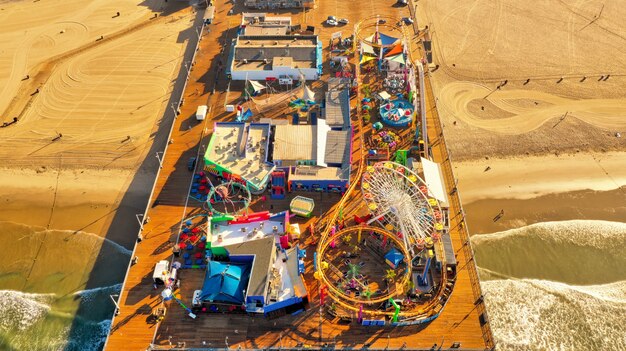 Toma panorámica de un parque de atracciones en un muelle de madera en la playa.