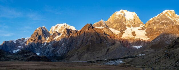 Toma panorámica de un valle en la base Cordillera Huyahuash, Perú con su pico cubierto de nieve.