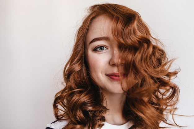 Toma de primer plano de atractiva chica elegante con el pelo rojo. Modelo de mujer bastante jengibre mirando con sonrisa juguetona.