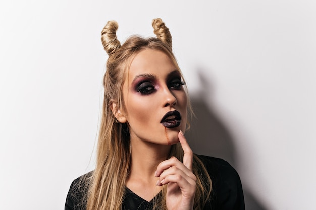 Toma de primer plano de vampiro hermoso. Foto interior de dama con maquillaje aterrador posando en halloween.