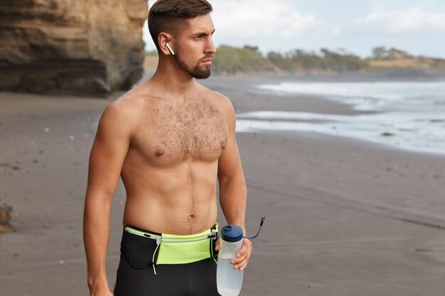 Toma recortada de hombre deportivo tiene cuerpo musculoso toma descanso y bebe agua dulce