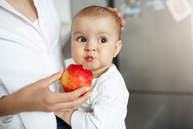 Toma recortada de la madre dando a bebé una rodaja de manzana