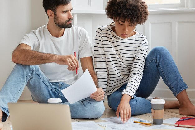 Toma recortada de mujer y hombre interracial cooperan para el proyecto