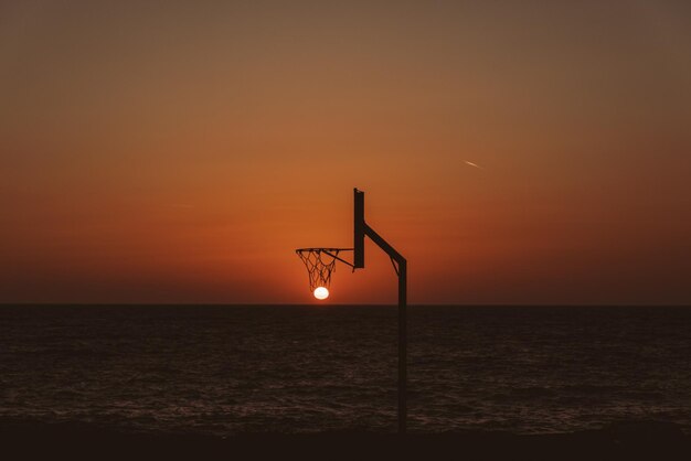 Toma de silueta de la puesta de sol en un aro de baloncesto - perfecto para papel tapiz