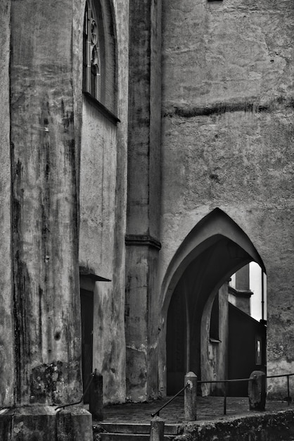 Toma vertical en escala de grises de un antiguo edificio histórico de piedra con una puerta en forma de arco