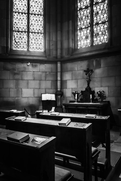 Foto gratuita toma vertical en escala de grises del interior de una iglesia cristiana con la biblia en cada escritorio