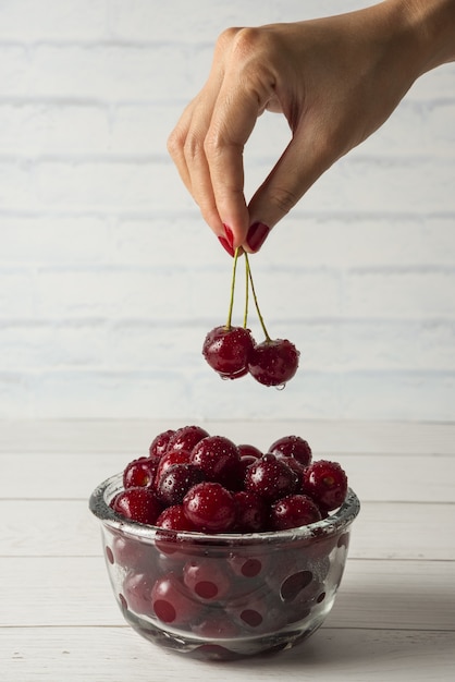 Foto gratuita tomando cerezas de un recipiente de vidrio aislado sobre fondo blanco.