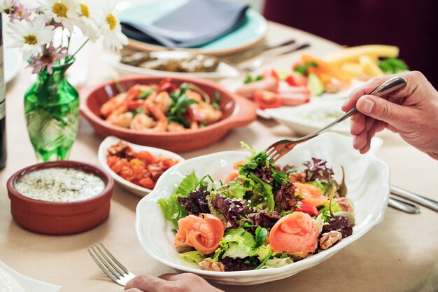 Tomando ensalada verde de tazón blanco con tenedor.