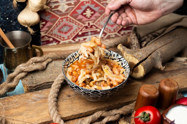 Tomando frijoles fideos del tazón con una cuchara.