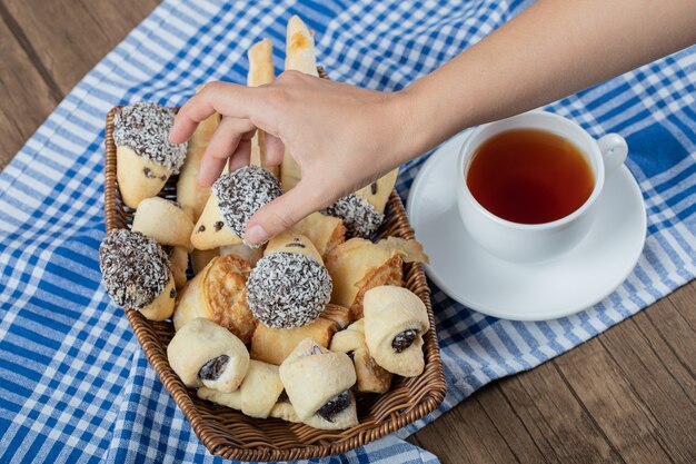 Tomando una galleta de chocolate de la bandeja de madera con una taza de té alrededor.