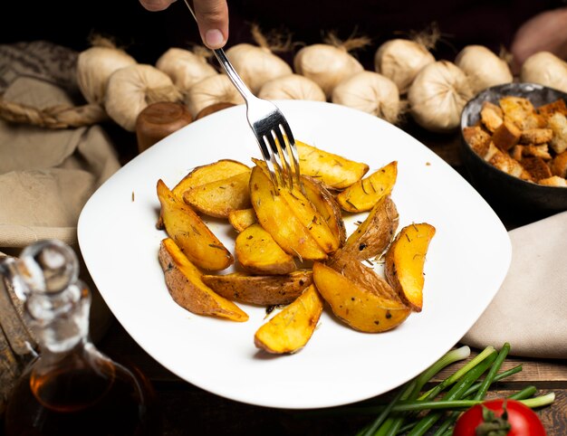 Tomando papas fritas del plato blanco con un tenedor