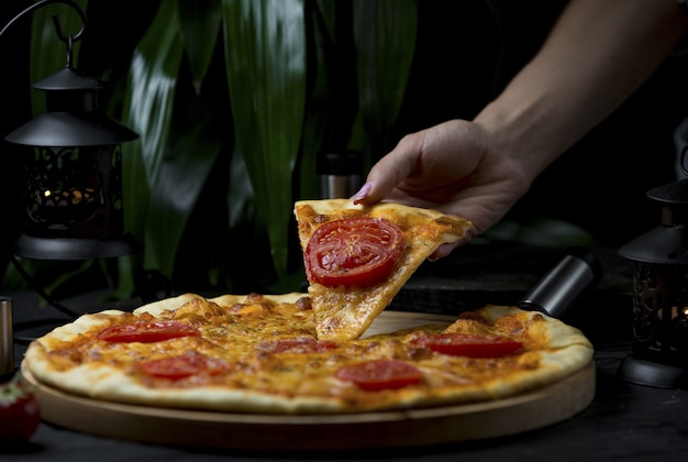 tomando una rebanada de pizza margarita con rodajas de tomate