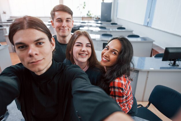 Tomando una selfie. Grupo de jóvenes en ropa casual que trabajan en la oficina moderna