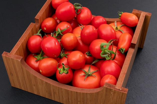 Foto gratuita tomate en caja de madera sobre superficie de piedra negra