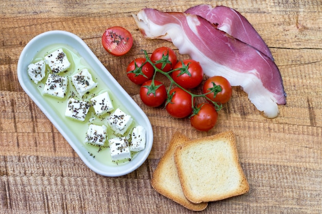 Tomate cherry, queso y prosciutto con pan tostado en la mesa de madera