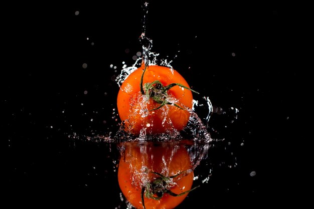 El tomate con gotas se encuentra en el fondo negro