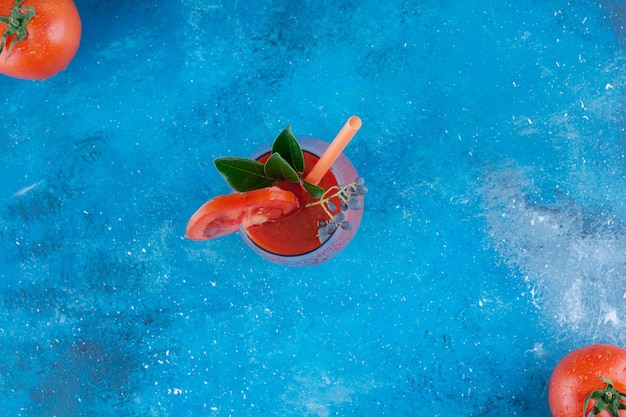Tomate maduro y jugo de tomate en el tablero, sobre fondo azul. Foto de alta calidad
