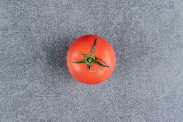 Un tomate rojo fresco sobre una superficie de mármol