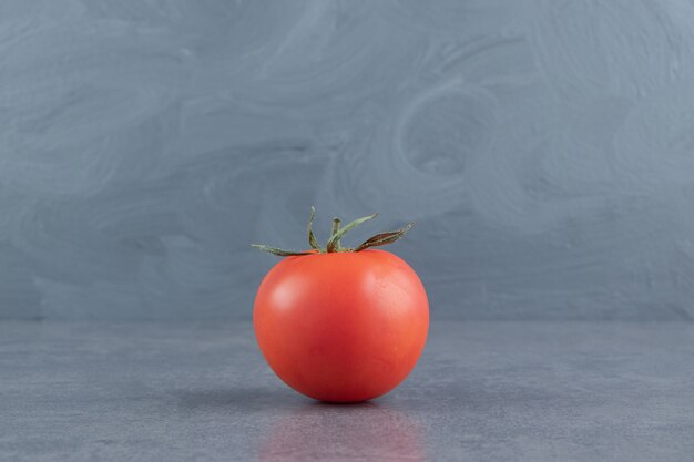 Foto gratuita un tomate rojo fresco sobre una superficie de mármol