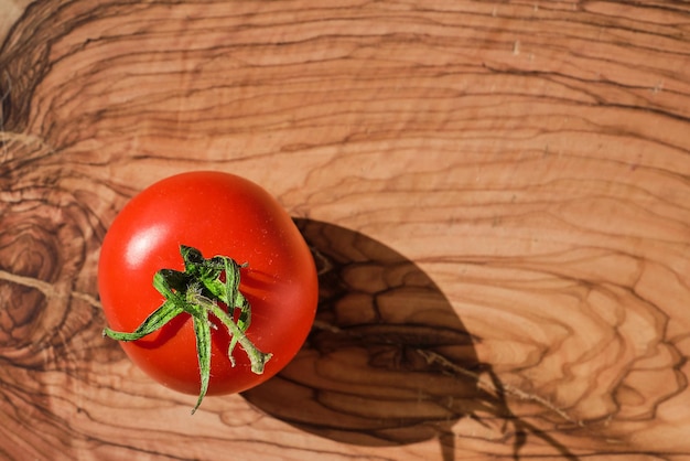 Tomate rojo maduro de una granja orgánica en una tabla de cortar de madera vista superior de luz solar brillante con espacio de copia preparando un plato