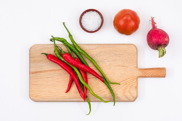 Tomate rojo, rábano, pimiento rojo y verde con tabla de cortar de madera