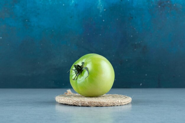 Tomate verde con cuerda sobre mármol.