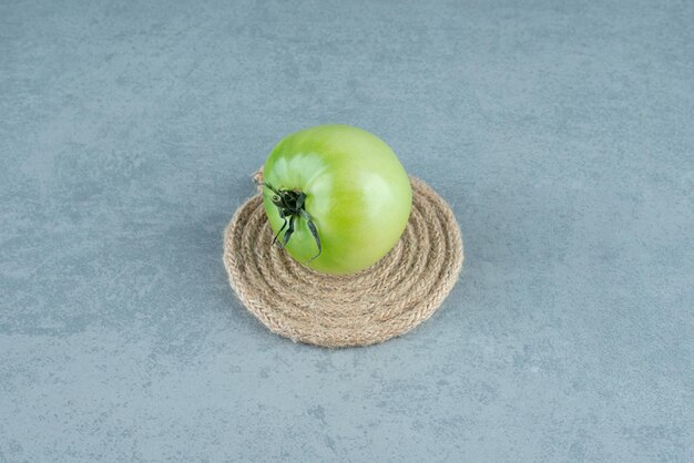 Tomate verde con cuerda sobre mármol.