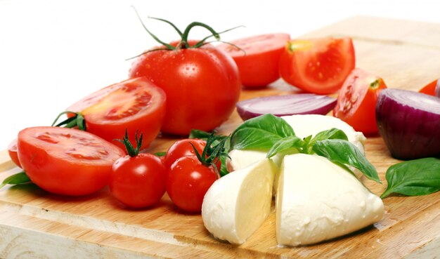 Tomates, albahaca y mozzarella sobre tabla de madera