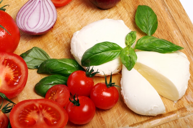 Tomates, albahaca y mozzarella sobre tabla de madera