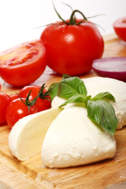 Tomates, albahaca y mozzarella sobre tabla de madera