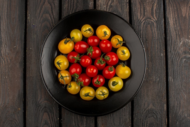 Foto gratuita tomates amarillo y rojo en forma redonda dentro de la placa negra sobre un rústico